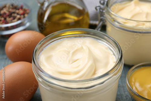 Delicious homemade mayonnaise with ingredients on light blue wooden table, closeup