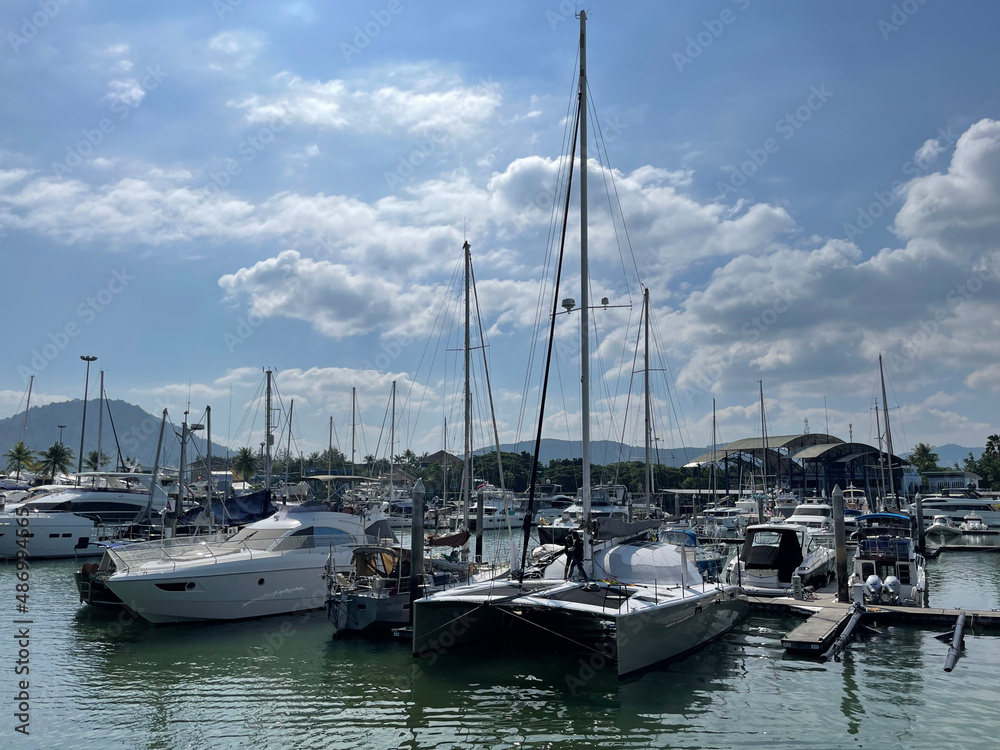 Sea harbor. Yacht club. Boats moored at the bay. Beautiful clouds. High masts of sailboats are directed to the sky. Yacht maintenance personnel, staff, navigation season. Luxury yachts, marina. Summer