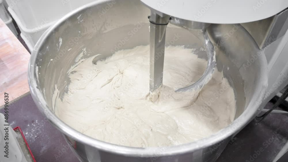 Baker taking out dough of a kneading machine at industrial bakery. High quality 4k footage
