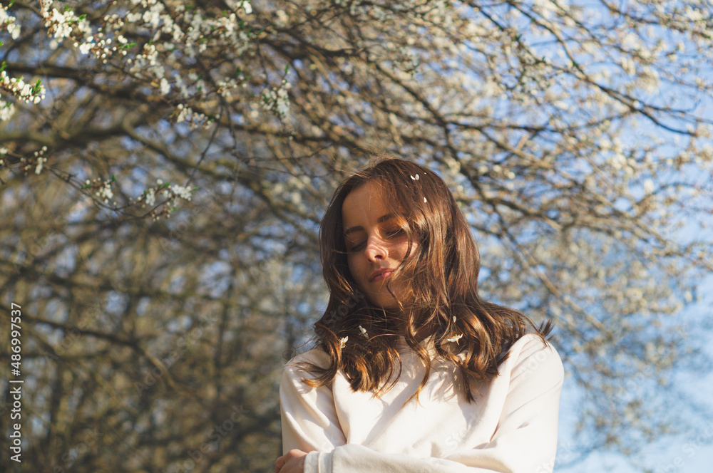 Portrait of young beautiful woman among flowering trees. A woman rejoices in spring flowers. Breathe free. Happy woman no allergies. Spring allergy concept. Fashion and beauty. Spring concept Portrait of young beautiful woman among flowering trees. A woman rejoices in spring flowers. Breathe free. Happy woman no allergies. Spring allergy concept. Fashion and beauty. Spring concept