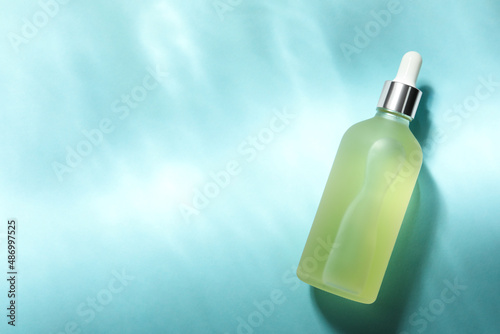 Bottle of hydrophilic oil on light blue background, top view. Space for text photo