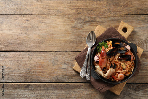 Delicious spaghetti with seafood served on wooden table  top view. Space for text