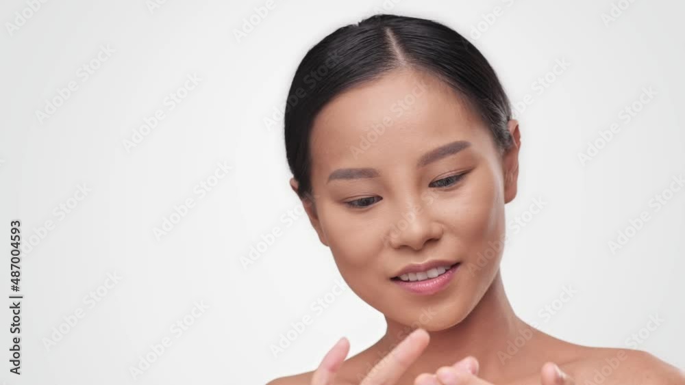 Close up Portrait young asian woman uses creams for the beauty of her face for fresh moisturized skin. Smile beautiful close up cosmetic face. Happy healthy model on white isolate background in studio Close up Portrait young asian woman uses creams for the beauty of her face for fresh moisturized skin. Smile beautiful close up cosmetic face. Happy healthy model on white isolate background in studio
