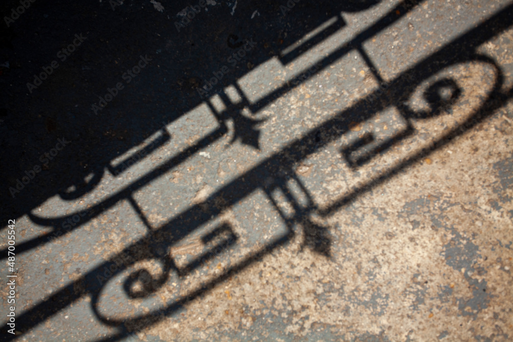 Fototapeta premium Geometric pattern fence shadow on sidewalk