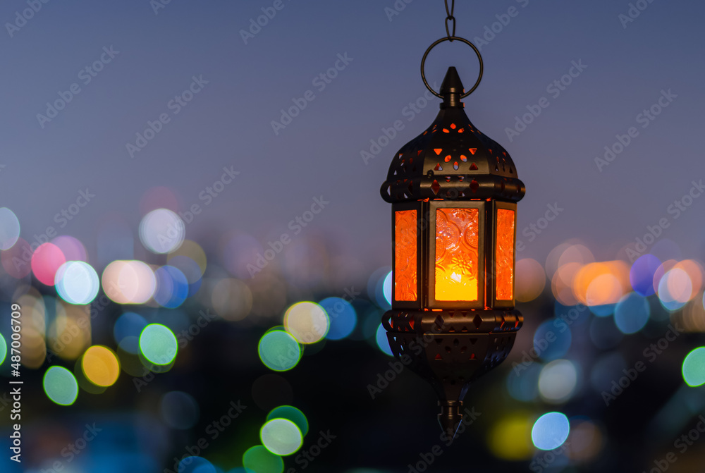 Hanging lantern with night sky and city bokeh light background for the Muslim feast of the holy month of Ramadan Kareem.