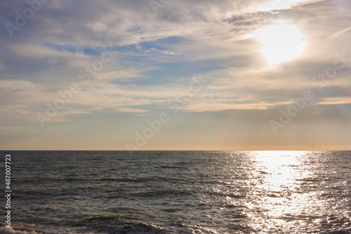 Gray stormy sea at sunset. In a cloudy sky  the sun goes down below the horizon.