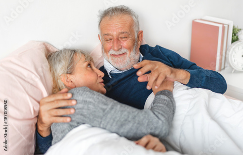 Senior happy love elder couple relaxing and talking together lying on bed in bedroom at home.Retirement healthcare couple concept