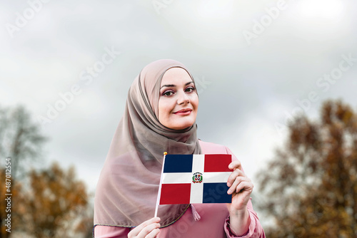 Muslim woman in hijab holds flag of Dominican Republic 