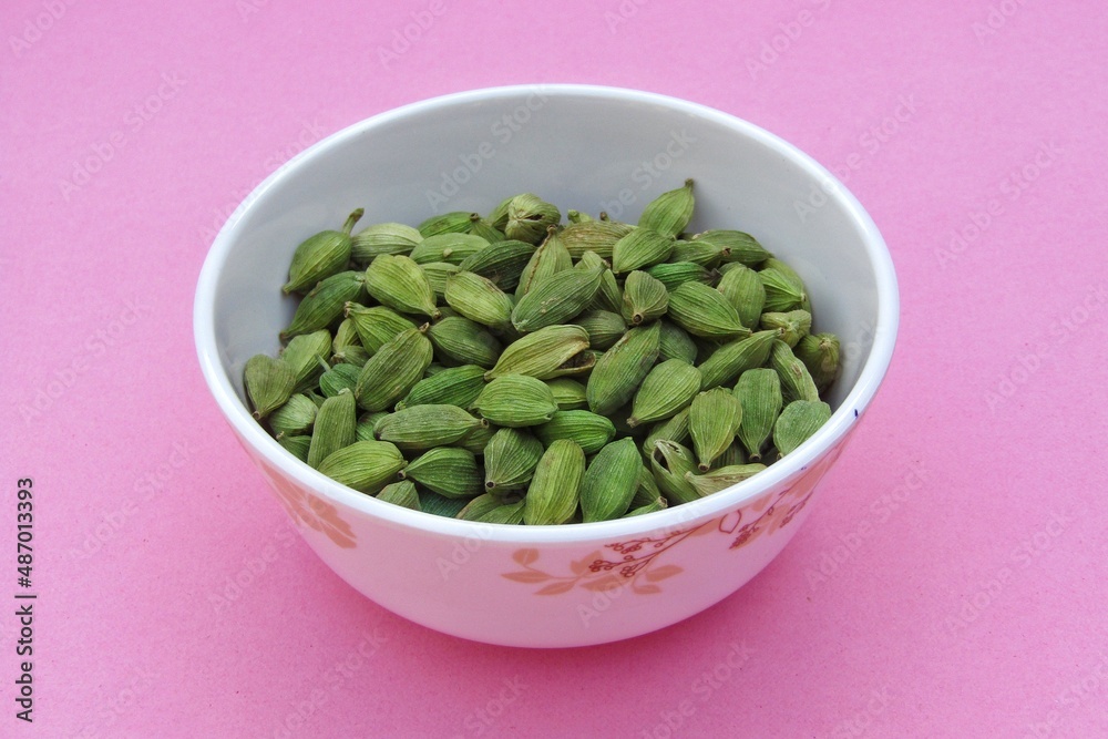 Cardamom in a bowl on pink background 