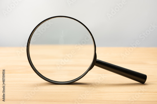 Magnifying glass black color on wooden table. Research, searching or investigating something. front view Magnifying glass