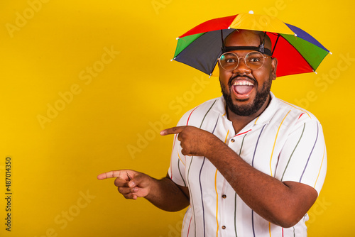 handsome brazilian afro man, dressed for carnival, typical brazilian party, carnival, revelry, party. with hands and fingers pointing to the side, advertising, advertising, copy space, negative space. photo