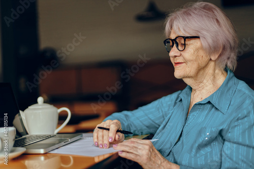 A businesswoman with glasses sits at a table in front of a laptop Freelancer works unaltered