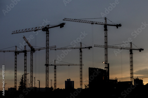Beautiful night view of the construction of new houses. High construction cranes against the background of the night sky.