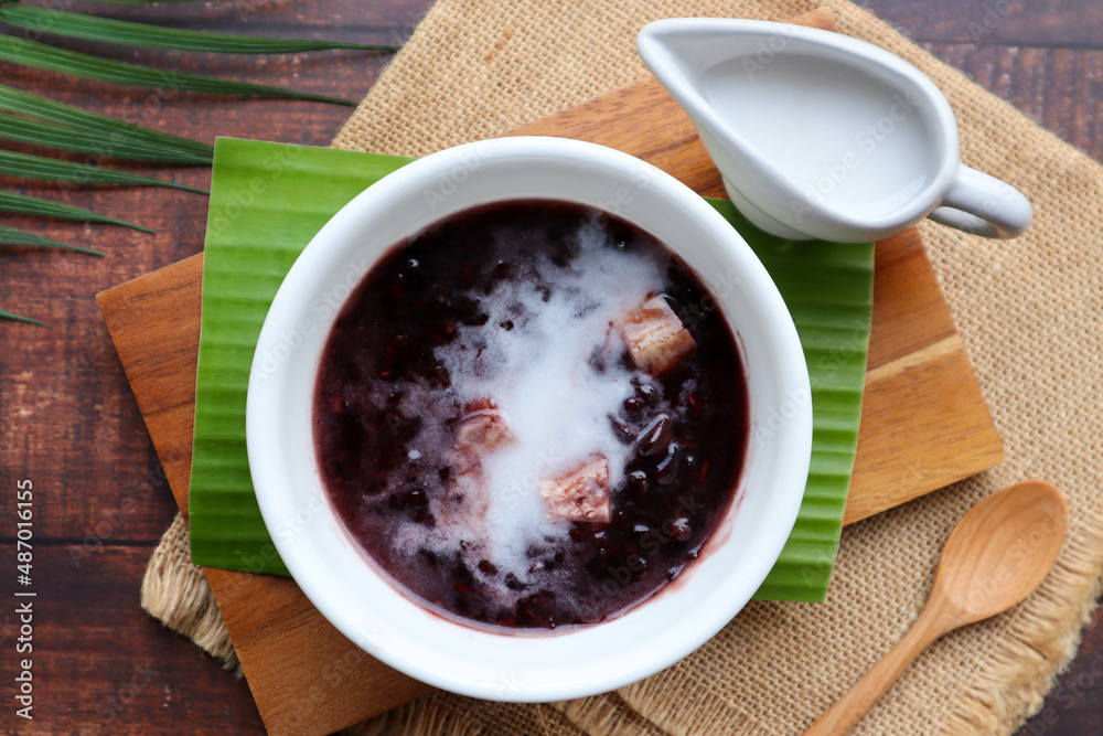 Black sticky rice pudding with taro and coconut milk at top view of wood table, Black glutinous rice - Thai dessert called Khao Nieow Dam Black sticky rice pudding with taro and coconut milk at top view of wood table, Black glutinous rice - Thai dessert called Khao Nieow Dam