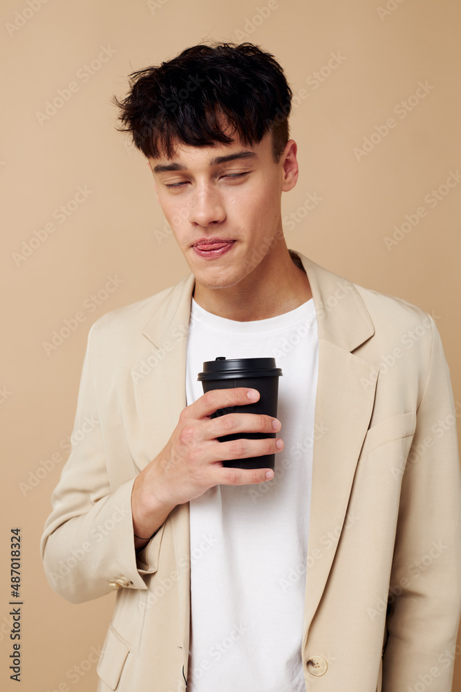 Photo young boyfriend black disposable glass in the hands of posing fashion light background unaltered Photo young boyfriend black disposable glass in the hands of posing fashion light background unaltered
