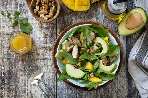 Healthy diet salad with turkey, arugula, mango, avocado and vinaigrette dressing on a rustic countertop. Top view flat lay background.