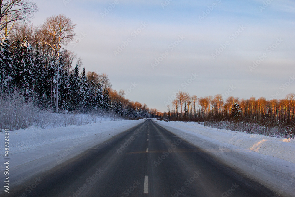 Winter track in the Siberian taiga. An icy winter highway runs through the snow and taiga. A section of the highway in the Khanty-Mansi Autonomous Okrug - Yugra between Khanty-Mansiysk and the city of