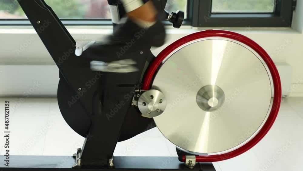Exercise bike indoor. Closeup of spinning wheels. Woman exercising at home on spin indoor bicycle doing fitness workout
