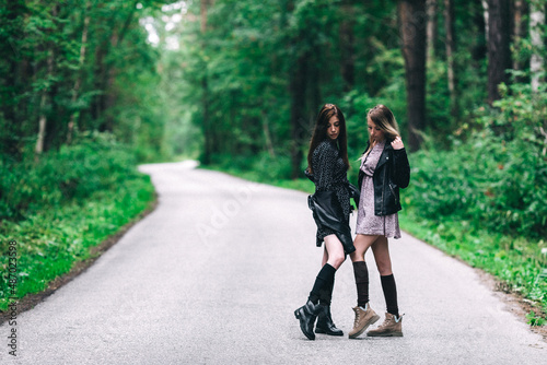 Fototapeta Naklejka Na Ścianę i Meble -  Two girls, blonde and brunette on the road in the summer forest