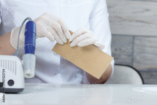 Professional manicurist opens a paper bag with sterile manicure tools. Preparing for customer service in nail beauty salon.