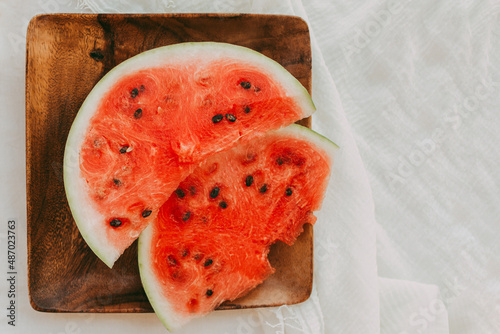 Fresh striped sliced watermelon on a wooden tray on a white tablecloth. Picnic in nature