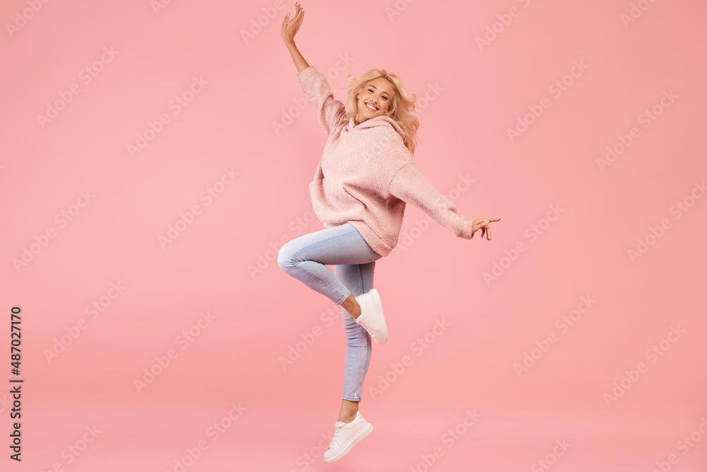 Playful caucasian woman jumping and having fun over pink studio background, lady posing in mid-air Playful caucasian woman jumping and having fun over pink studio background, lady posing in mid-air