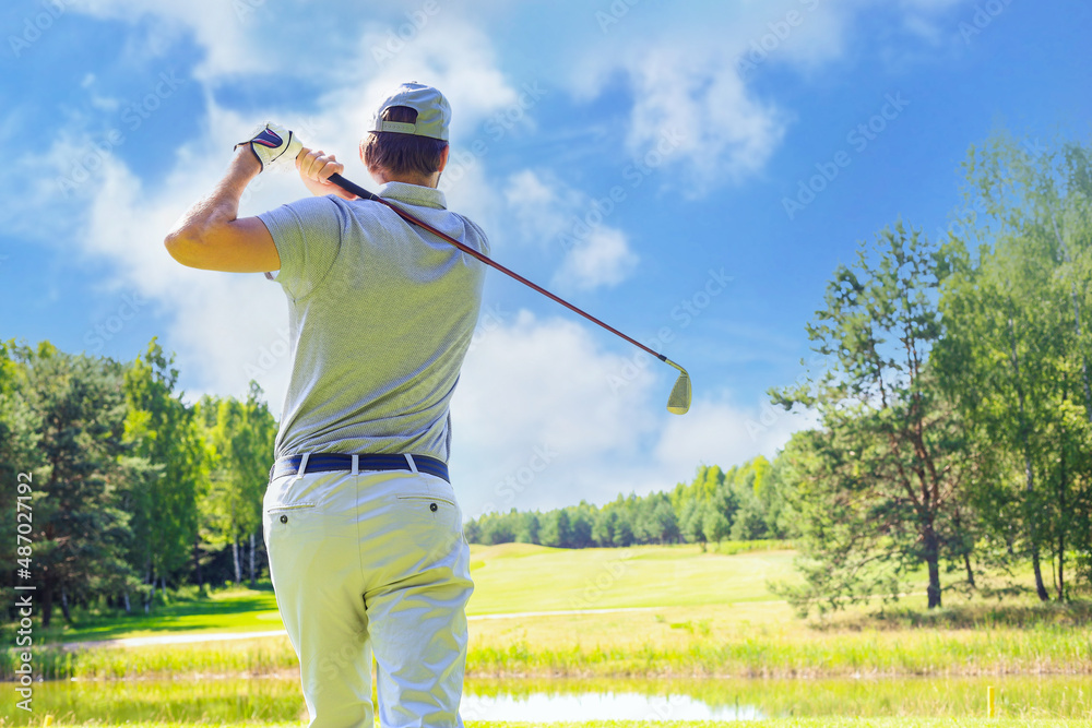 Golfer hits an fairway shot towards the club house. Golfer hits an fairway shot towards the club house.
