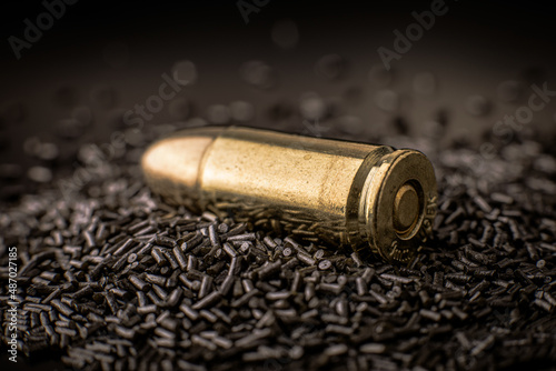 Macro shot of a pistol cartridge in a pile of gunpowder, limited depth of field, soft focus