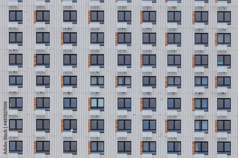 Fragment of the wall of a multi-storey white building with windows