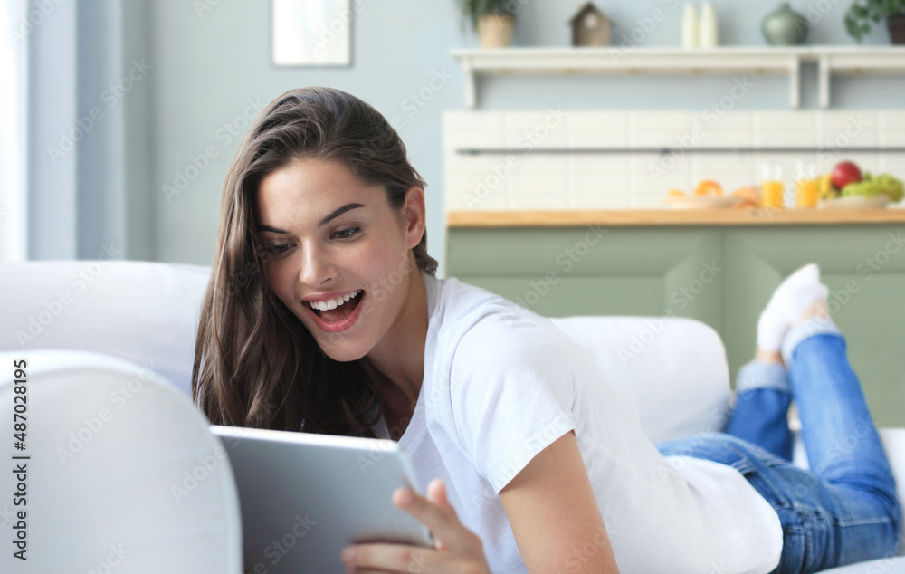 Beautiful young woman using tablet sitting on sofa at home at living room. Beautiful young woman using tablet sitting on sofa at home at living room.