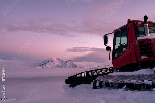 Snowplow machine at snowy ski resort at sunset