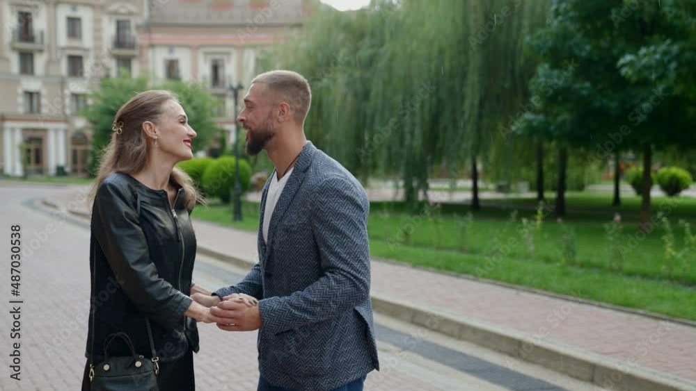 a blonde in a black jacket and a man with a beard joined hands and danced under the raindrops on a city street. the camera is moving a blonde in a black jacket and a man with a beard joined hands and danced under the raindrops on a city street. the camera is moving
