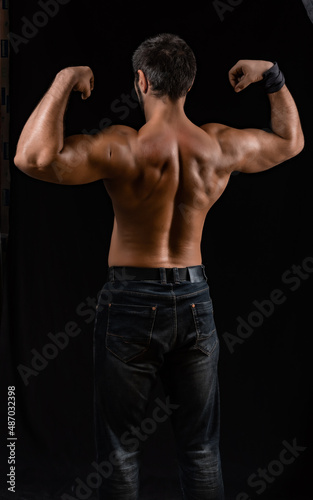 muscular man. athlete posing in a black T-shirt and jeans. studio portrait