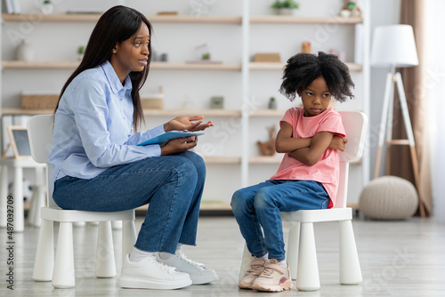 Child psychologist having conversation with defiant little girl