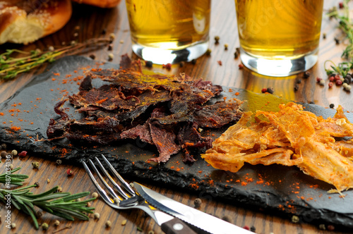 dried meat slices on black slate with beer on the table
