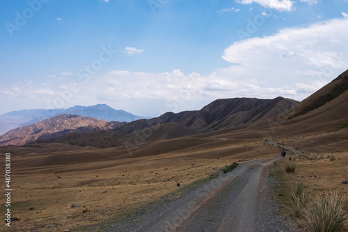 Gravel road in the mountains with sky background. Road to Bartogay reservoir from Assy plateau.