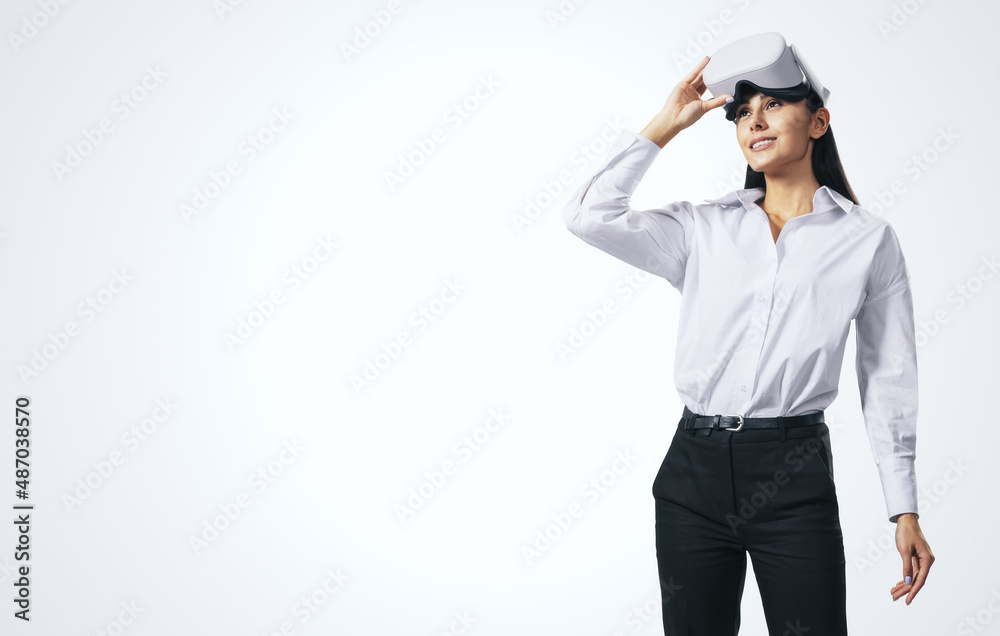 Virtual reality and technology concept with young woman looking up and VR headset on her head isolated on abstract light background with copyspace, mockup Virtual reality and technology concept with young woman looking up and VR headset on her head isolated on abstract light background with copyspace, mockup
