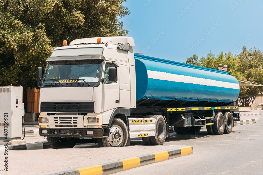 Water tank trailer unit, prime mover, refuel at gas and oil station in sunny summer day. Water tank trailer parked near oil station. Water tank trailer unit, prime mover, refuel at gas and oil station