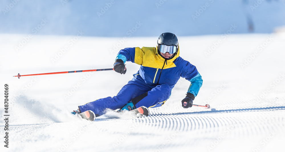 A young aggressive skier on an alpine slope demonstrates an extreme carving skiing style. - obrazy, fototapety, plakaty 