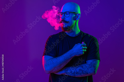 adult man is using electronic cigarette, exhaling vapor in studio. color filters. Vaping concept