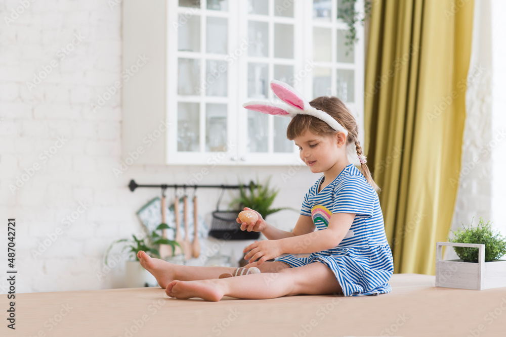 Happy easter! Happy family preparing for Easter. A cute child girl wears rabbit ears holds a basket with painted eggs in the kitchen of the house. Happy easter! Happy family preparing for Easter. A cute child girl wears rabbit ears holds a basket with painted eggs in the kitchen of the house.