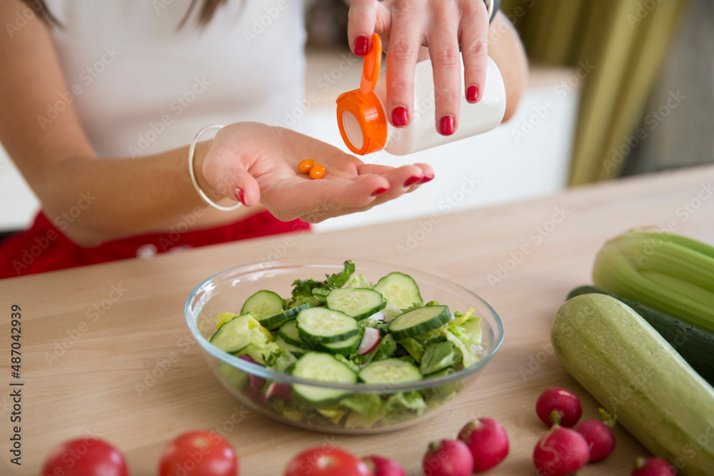 healthy lifestyle. Supporting immune system. woman takes vitamins. vitamin supplements for beauty, skin, hair, with green vegan food. at lunch at home healthy lifestyle. Supporting immune system. woman takes vitamins. vitamin supplements for beauty, skin, hair, with green vegan food. at lunch at home