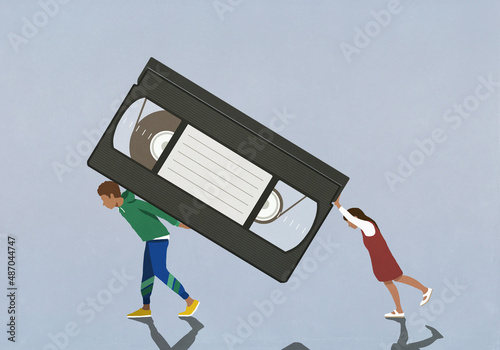 Boy and girl carrying large, antiquated VHS tape
 photo