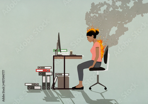 Businesswoman sitting at desk with back and head burning
