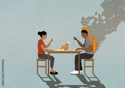 Couple eating turkey dinner at table, man's back on fire
 photo