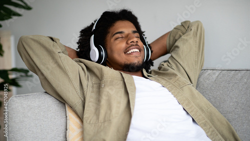 Pleased African American Guy Listening Music In Wireless Headphones At Home