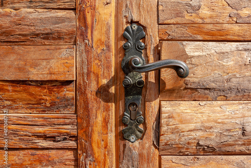 Vintage curly wrought iron handle on planked door. Horizontal photo.