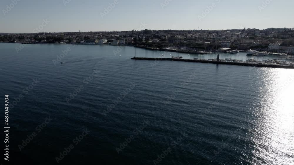 Aerial image filmed with a drone showing the town of Desenzano del Garda located on the shores of Lake Garda, northern Italy. Small port with sailing boats. Boats and yachts on the lake. Aerial image filmed with a drone showing the town of Desenzano del Garda located on the shores of Lake Garda, northern Italy. Small port with sailing boats. Boats and yachts on the lake.