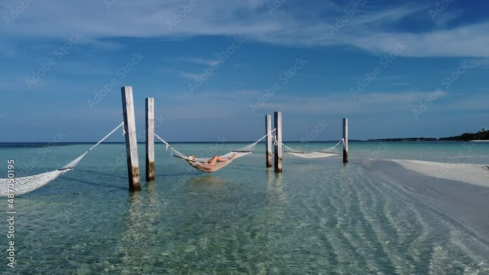 Middle aged woman resting on a hammock over the ocean Middle aged woman resting on a hammock over the ocean