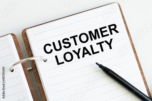 customer loyalty on notepad on white table, business concept